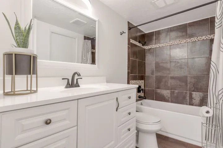 White vanity with a solid surface countertop, undermount sink, and dark bronze faucet
