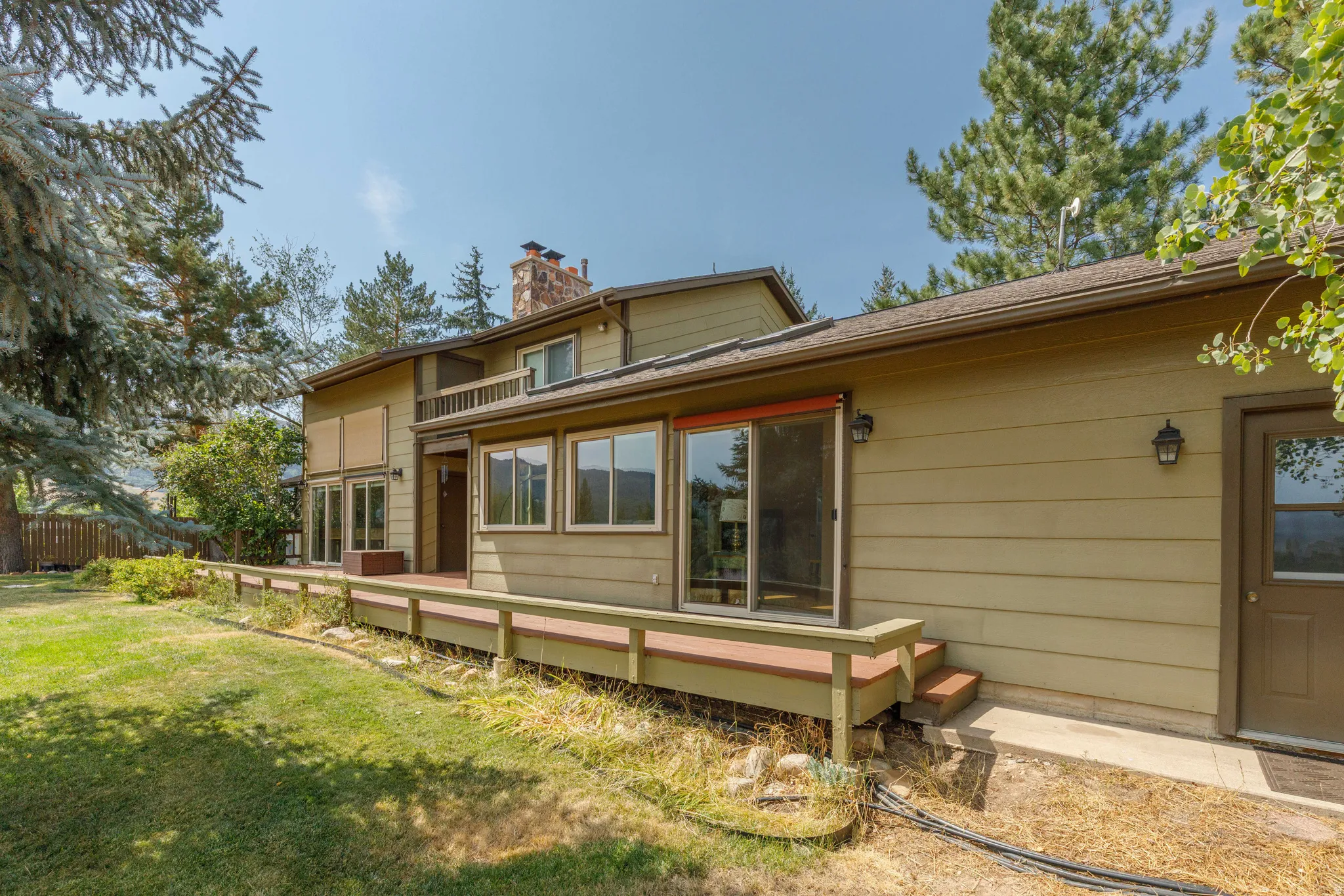 Expansive exterior deck space with railing, multiple windows, and a sliding glass door