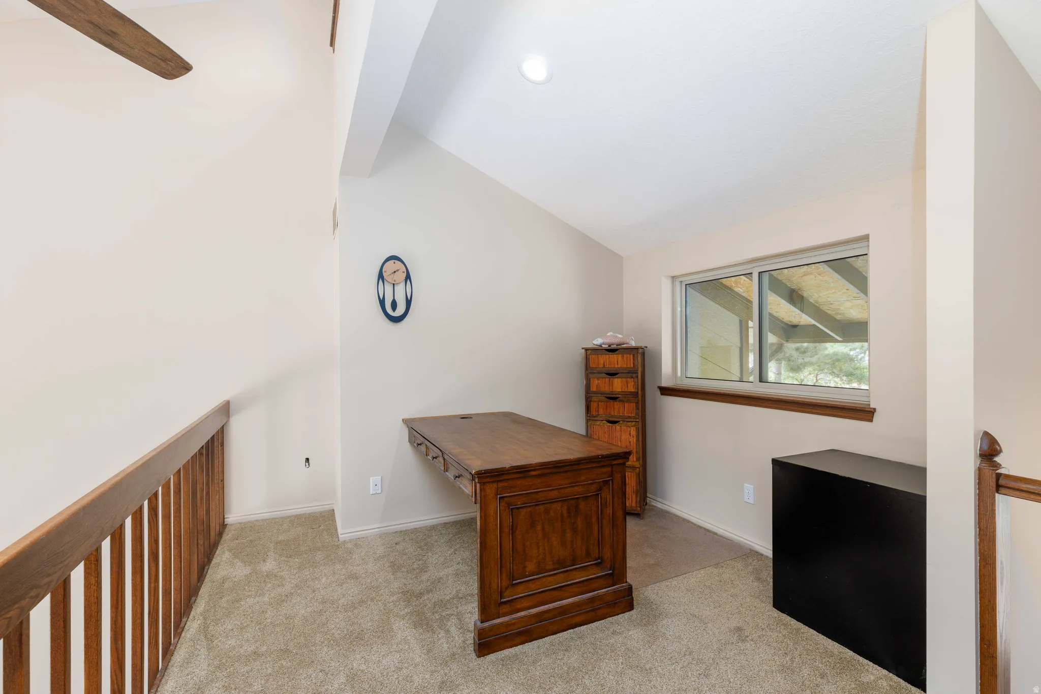 Carpeted loft area featuring a window, vaulted ceiling, and wood railing