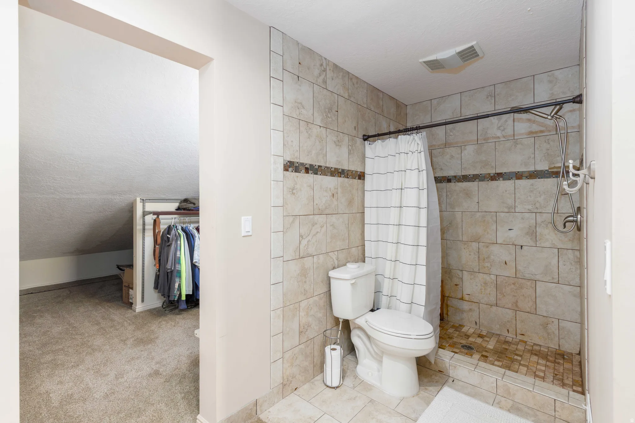 Tiled shower with a rainfall showerhead, accented by a decorative mosaic band