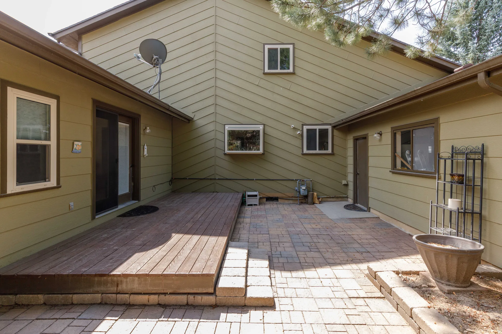 Outdoor living area featuring a wood deck, brick paver patio, and low retaining wall
