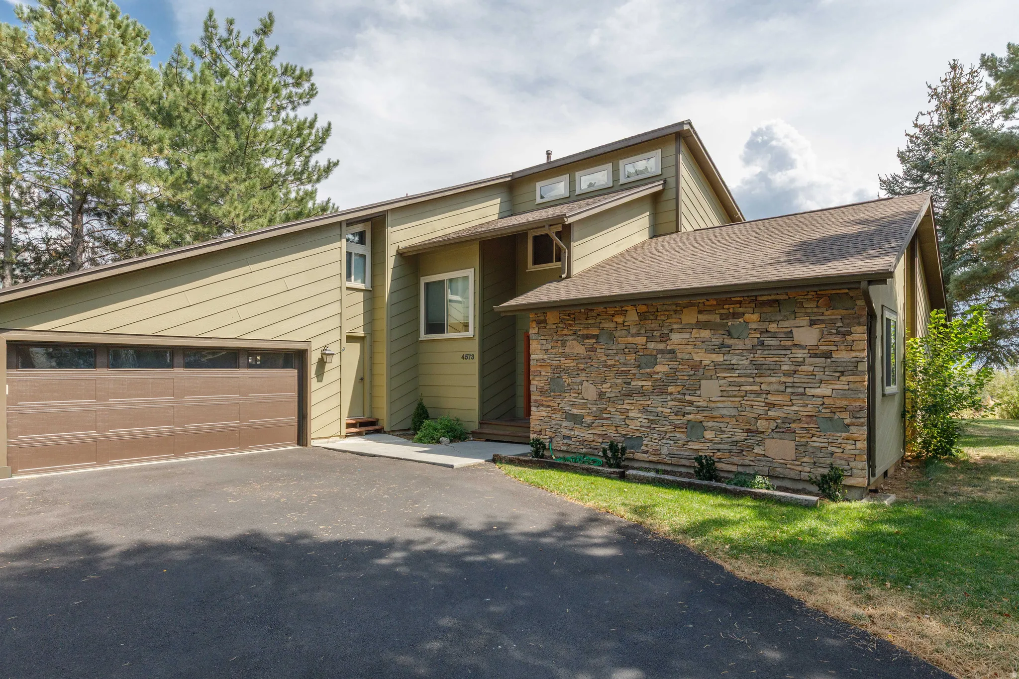 Multi-level exterior with textured siding and stone veneer accents