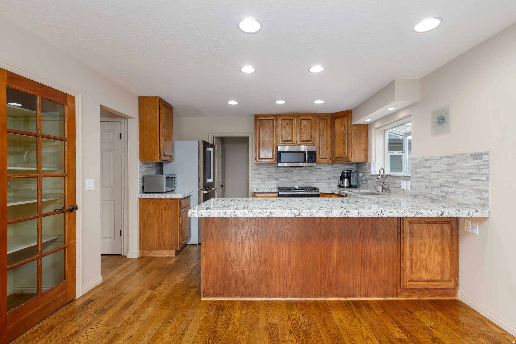 Kitchen featuring wood-finish flooring, recessed lighting, and a kitchen island with stone countertops
