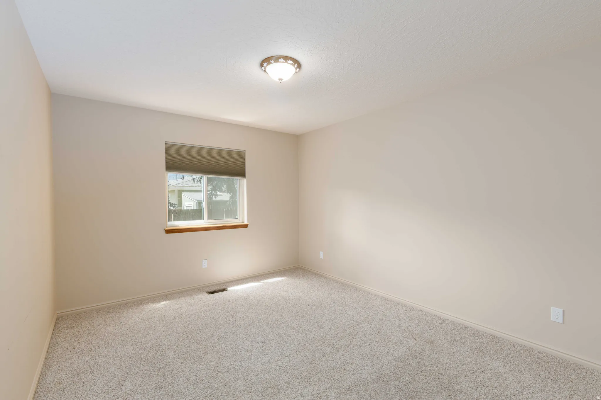 Light-toned walls, neutral carpeting, and a window with a wood-finish sill