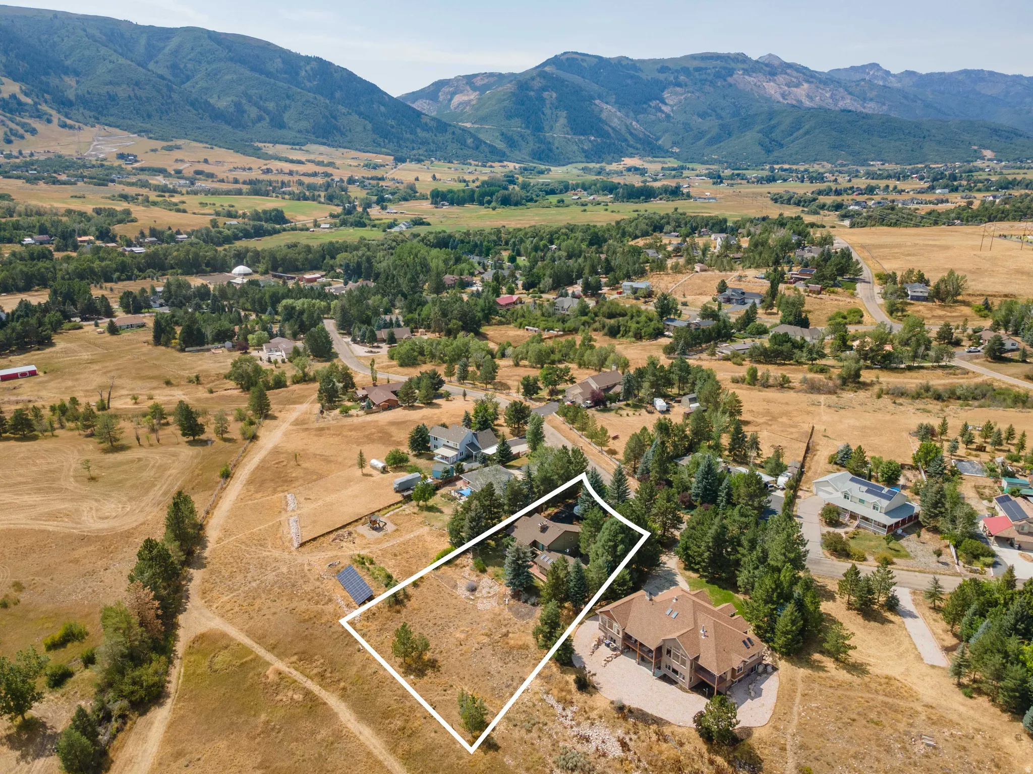 Expansive lot with mountain backdrop, surrounded by mature trees and residential properties