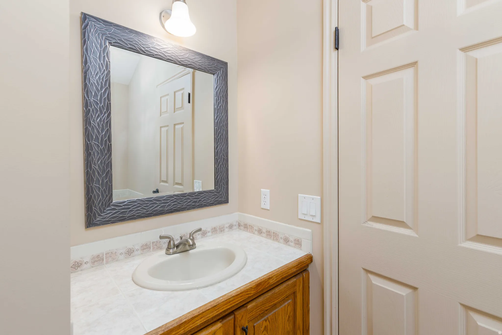 Vanity with wood-finish cabinetry, white countertop, and integrated sink