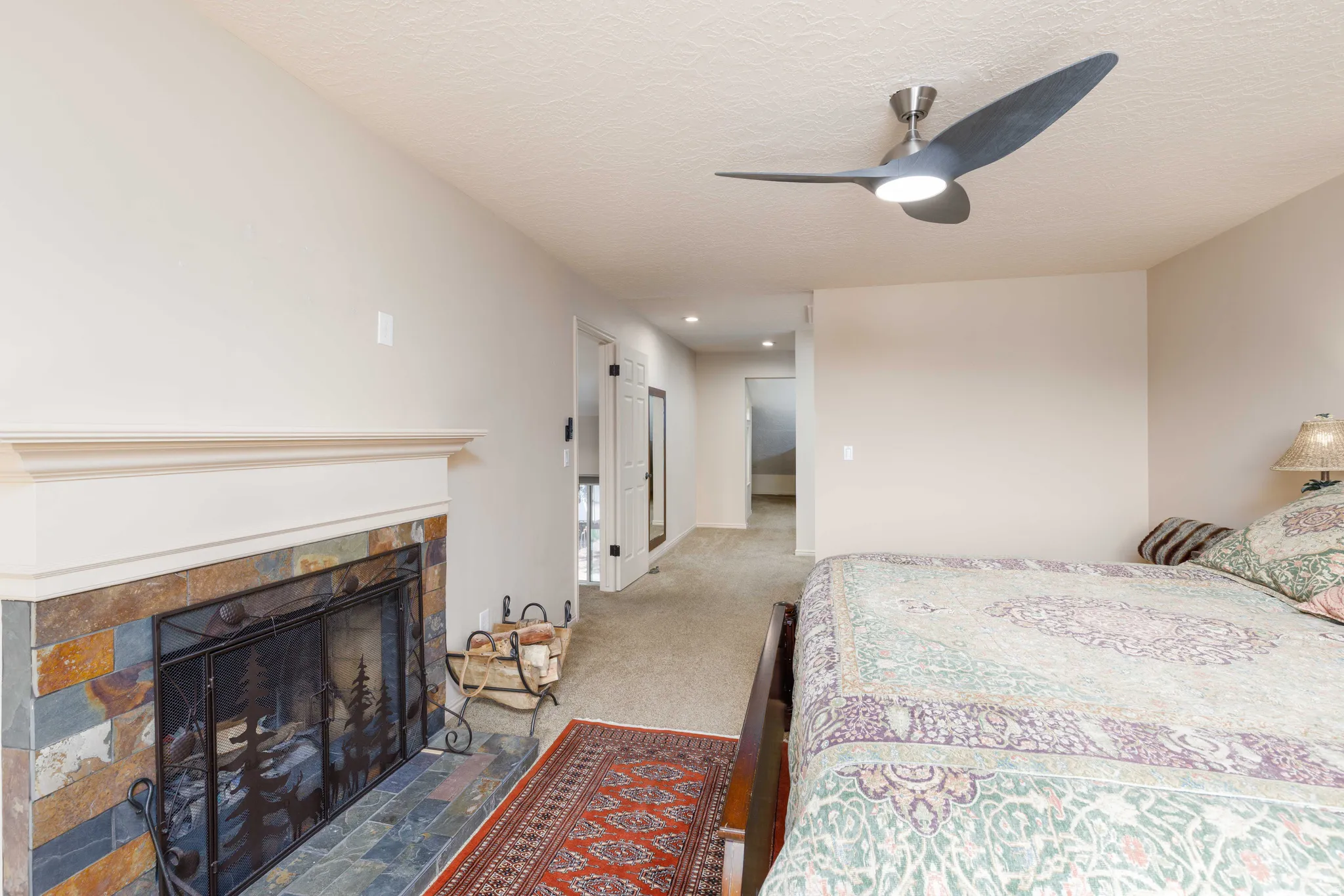 Stone-tile fireplace with a decorative metal screen and a painted wood mantel