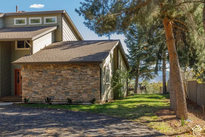 Exterior facade featuring horizontal siding, natural stone veneer accents, multi-level rooflines, clerestory windows, and mature trees