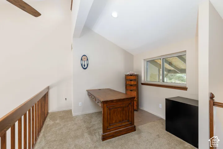 Carpeted loft area featuring a window, vaulted ceiling, and wood railing