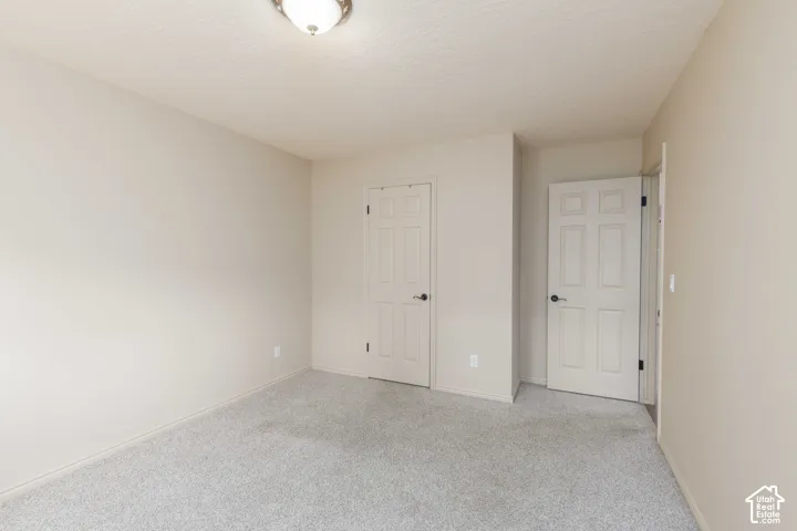 Neutral wall paint, textured ceiling, two paneled doors, carpet flooring, flush mount ceiling light fixture
