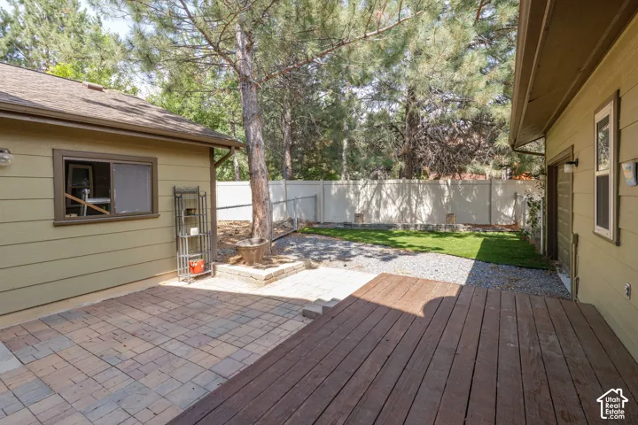 Spacious outdoor area featuring a wood deck, paver patio, gravel accents, and a section of green lawn