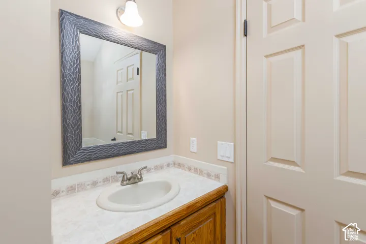 Vanity with wood-finish cabinetry, white countertop, and integrated sink