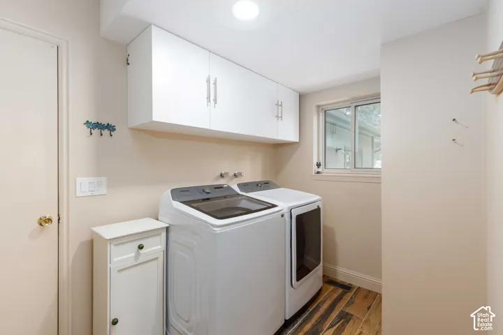 Wood-finish flooring, white overhead cabinetry with brushed nickel hardware, and a sliding window
