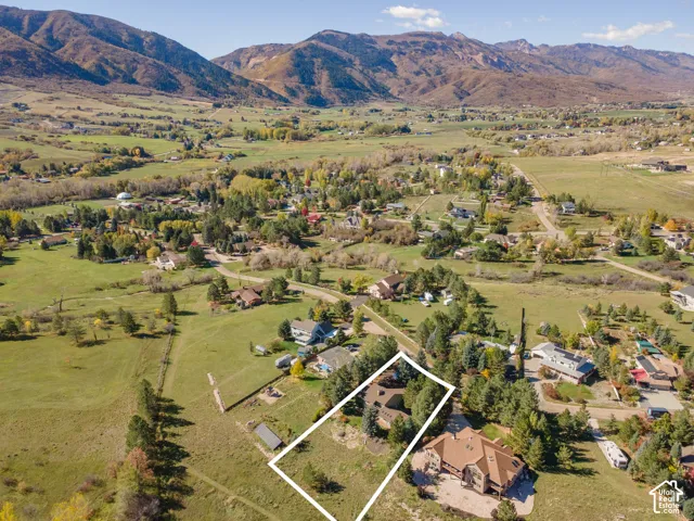 Aerial perspective featuring an expansive lot, mature evergreen trees, and proximity to mountain range terrain