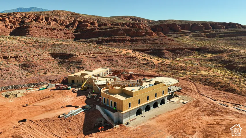 Expansive property featuring multiple structures under construction, set against a rugged mountain backdrop