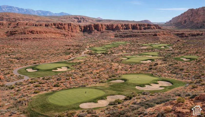 Desert landscape featuring multiple golf greens, sand traps, and winding cart paths, all set against a backdrop of natural rock formations