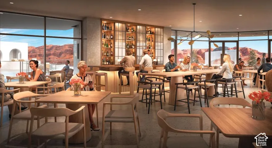 Spacious interior with expansive windows, a built-in bar with shelving, a large wood-finish communal table, and suspended modern lighting