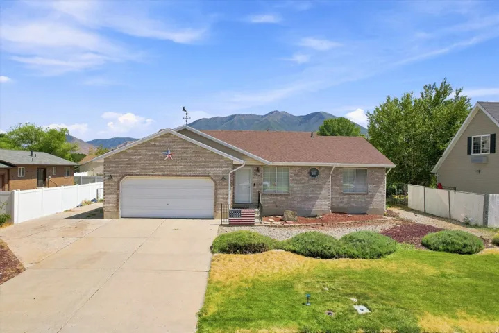 Brick facade home with an attached garage, paved driveway, and mountain backdrop