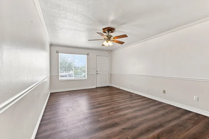 Wood-finish flooring, ceiling fan with light fixture, window with blinds, and white trim molding