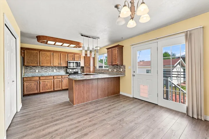 Kitchen featuring wood-finish cabinetry, stainless steel appliances, granite-style countertops, and a tile backsplash