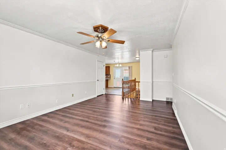 Wood-finish flooring, crown molding, chair rail molding, and a ceiling fan with integrated lighting