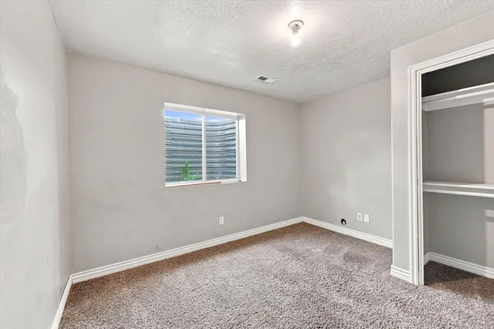 Carpeted room with a single window and an open closet