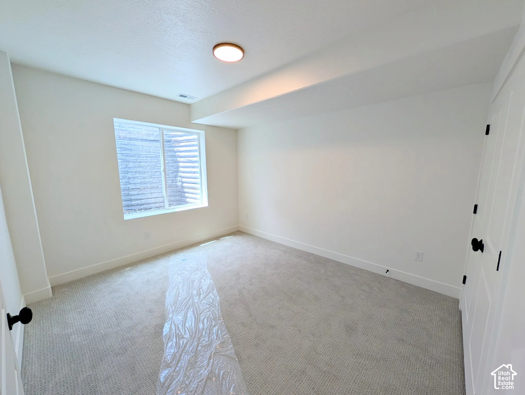 White walls with recessed window, light-colored carpeting, and white doors with black hardware