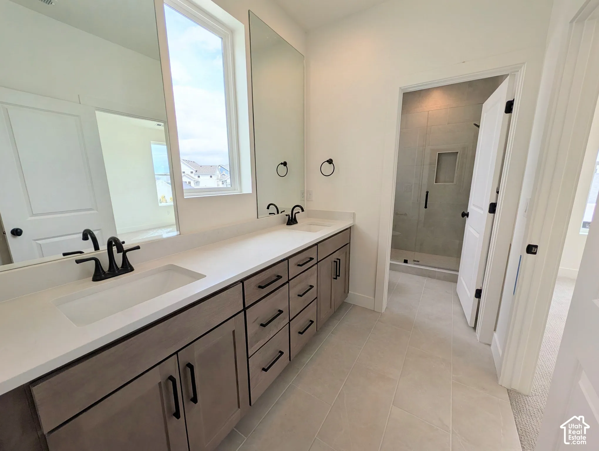 Primary bathroom Dual rectangular under-mount sinks with matte black fixtures, set into an expansive vanity with wood-finish cabinetry