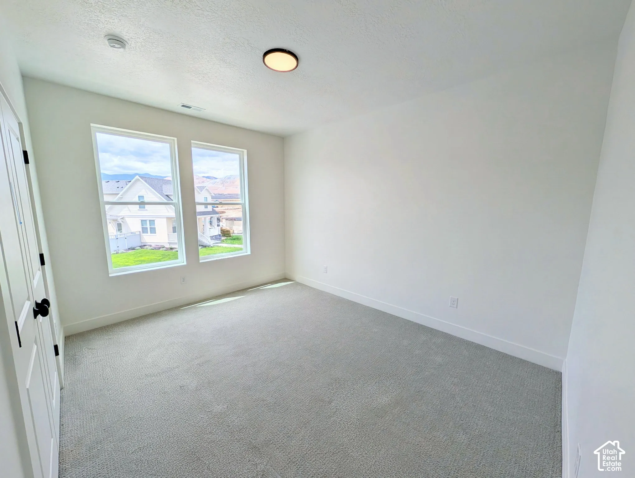 Light gray carpeting, white painted walls, and a contemporary ceiling fixture