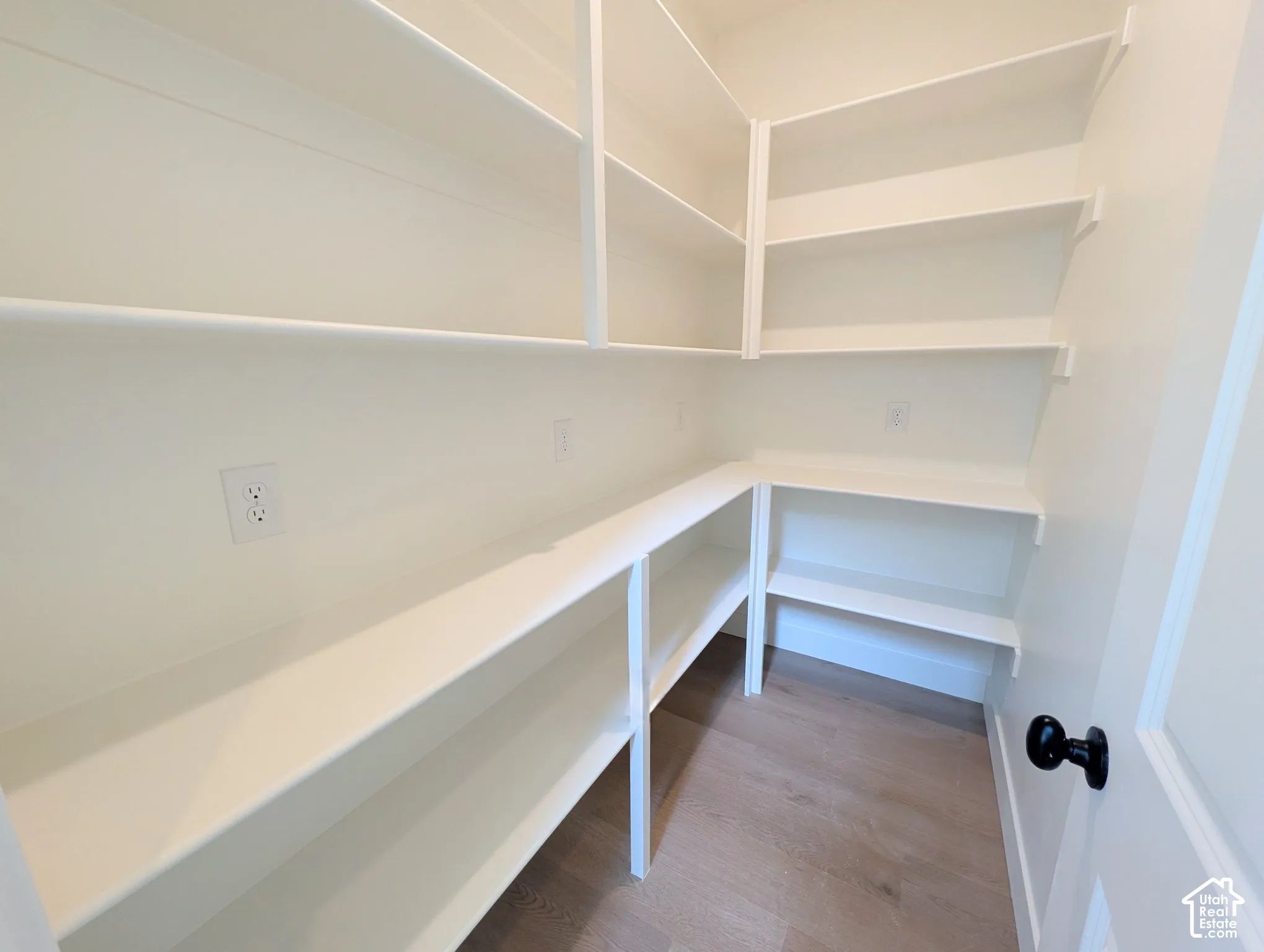 Custom built-in shelving, light wood-finish flooring, white painted walls, and a black door handle