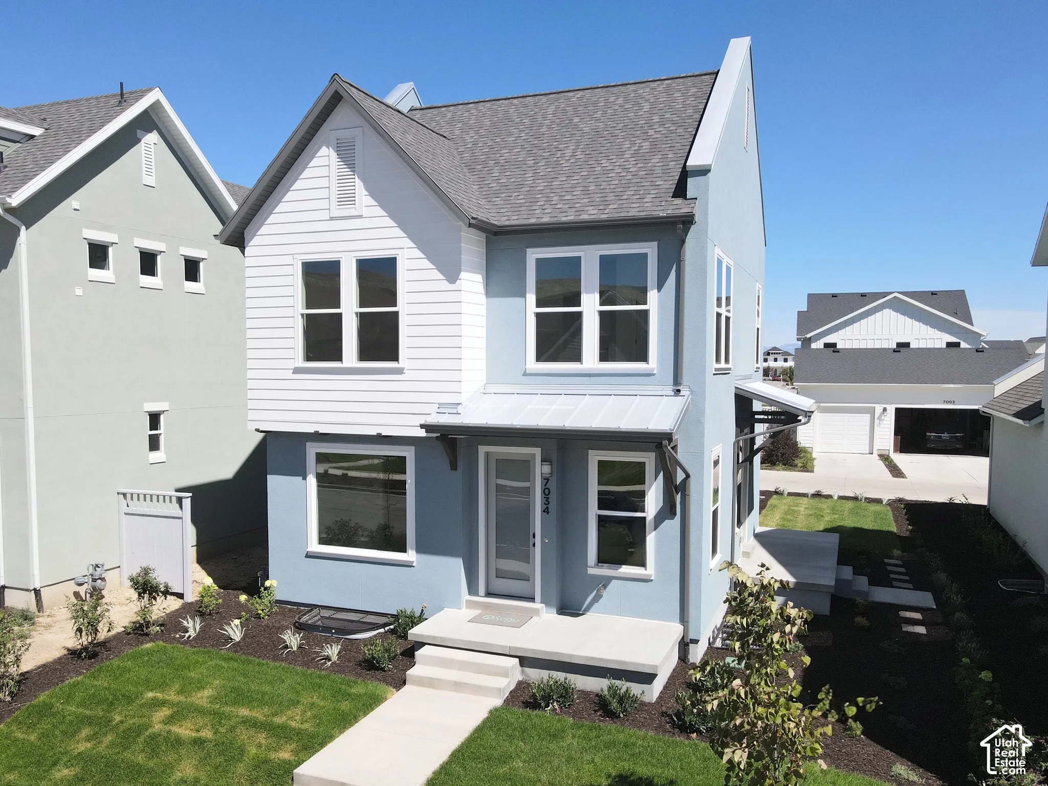 Two-story exterior with a mixed material facade, featuring a prominent front gable and a metal roof awning over the entry