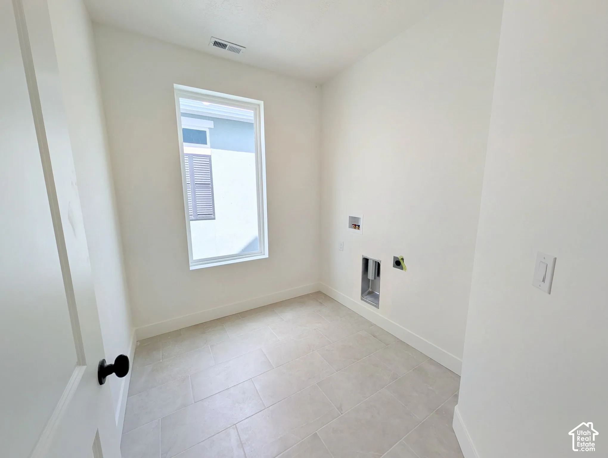 White walls, tile flooring, and a single window with white trim