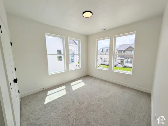 Multiple large windows, neutral wall finishes, light-toned carpet, recessed ceiling light fixture, white interior door with black hardware