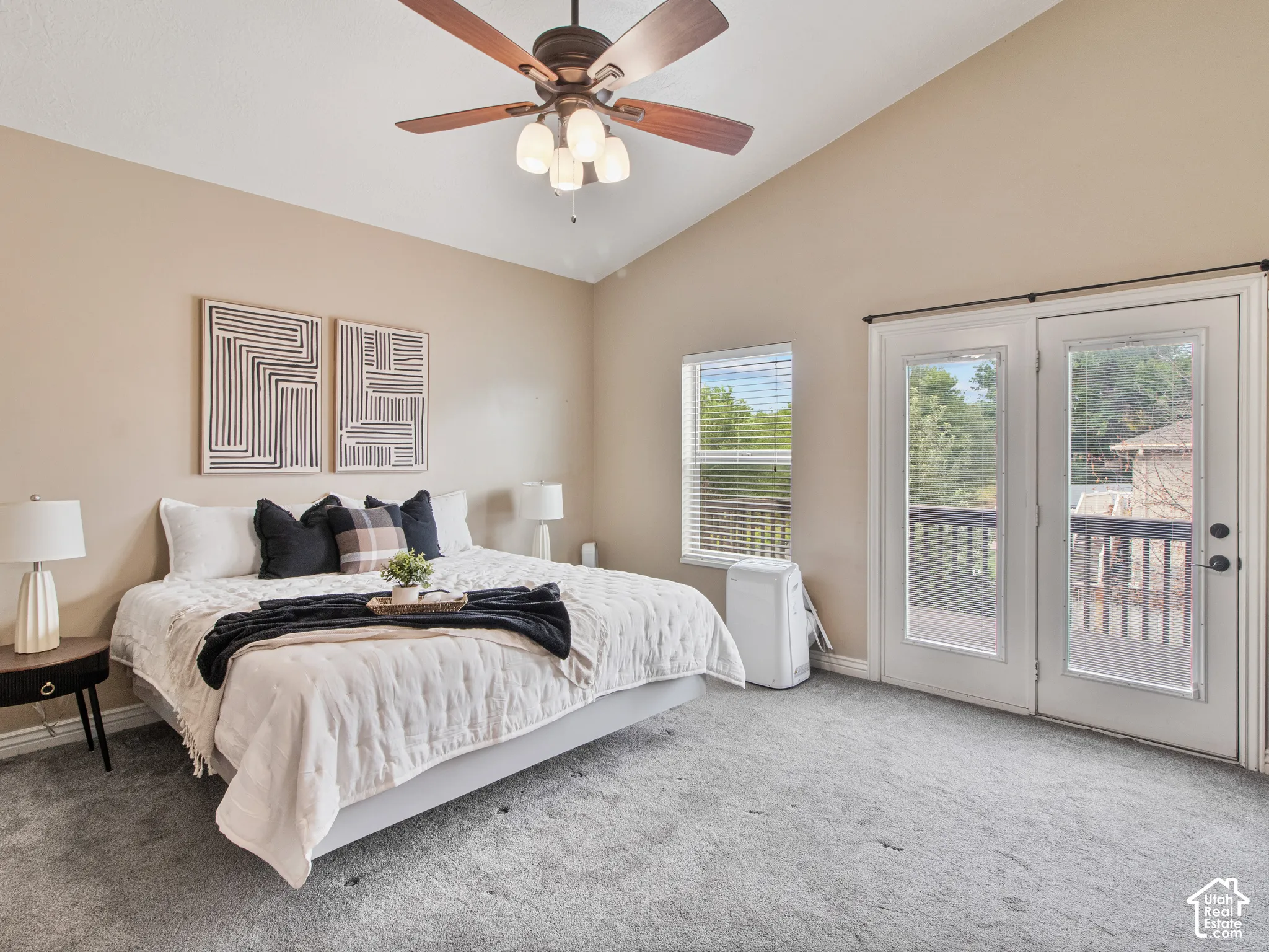 Master bedroom with vaulted ceiling with a ceiling fan, carpeted flooring, window with blinds, and French doors leading to an outdoor deck