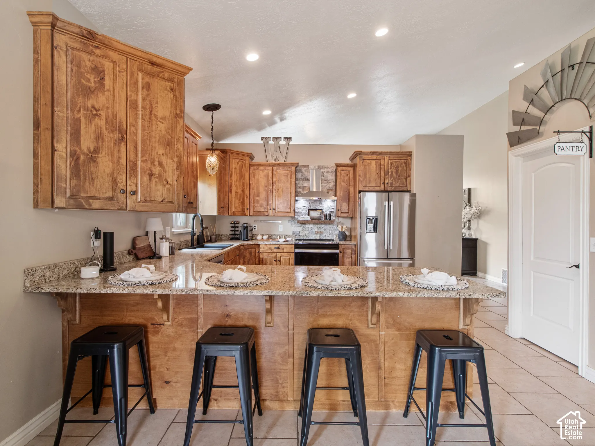 Chef's kitchen featuring warm wood cabinetry, stainless steel appliances, and a spacious granite-topped island with seating for four