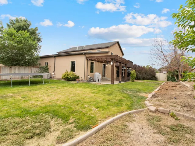Expansive backyard featuring a wood pergola and a concrete patio