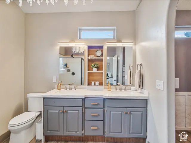 His & Her basin vanity with undermount sinks and modern fixtures, gray cabinetry with wood-finish hardware, built-in shelving, and a decorative light fixture