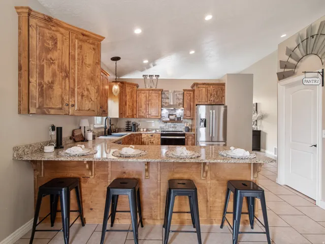 Chef's kitchen featuring warm wood cabinetry, stainless steel appliances, and a spacious granite-topped island with seating for four
