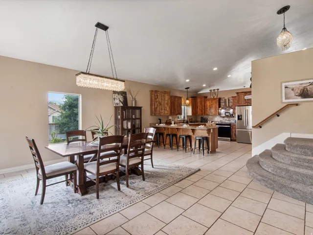 Open concept kitchen and dining area with tile flooring, stainless steel appliances, and wood cabinetry