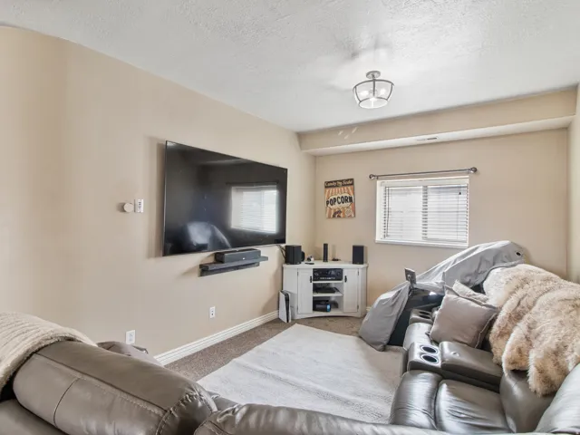 Recessed ceiling light fixture, window with blinds, carpeted flooring, and a mounted wall shelf