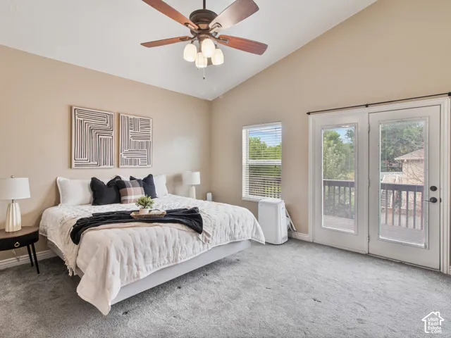 Master bedroom with vaulted ceiling with a ceiling fan, carpeted flooring, window with blinds, and French doors leading to an outdoor deck