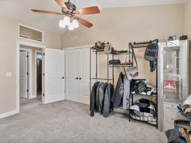 Vaulted ceiling with a ceiling fan, light gray carpeting, and two white bi-fold closet doors