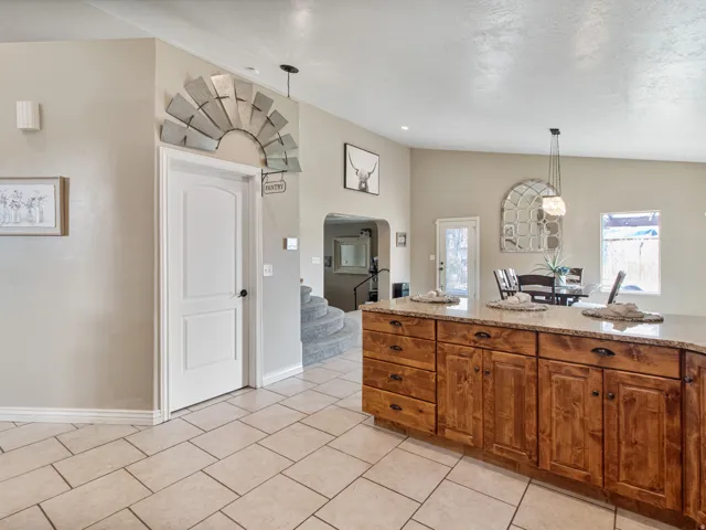 Spacious kitchen featuring an island with wood-finish cabinetry, granite-style countertop, and tile flooring