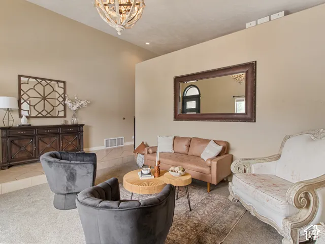 Vaulted ceiling with an ornate chandelier, neutral wall tones, and recessed lighting