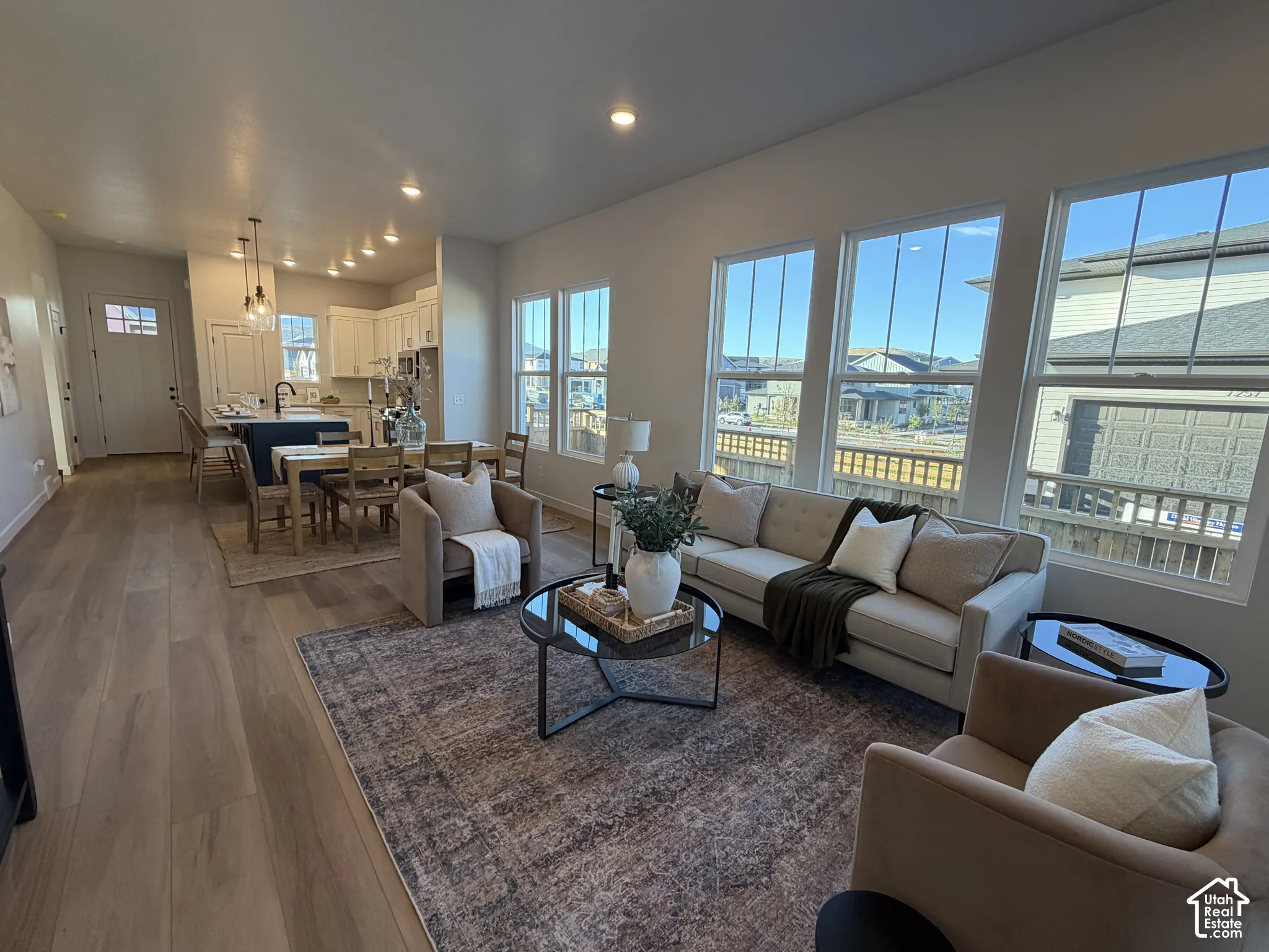 Open-concept living area with wood-finish flooring, recessed lighting, and multiple windows