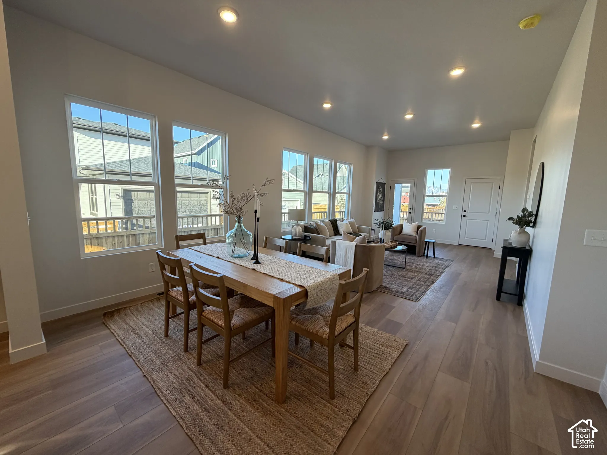 Spacious open-concept living area featuring wood-finish flooring, recessed lighting, and multiple large windows