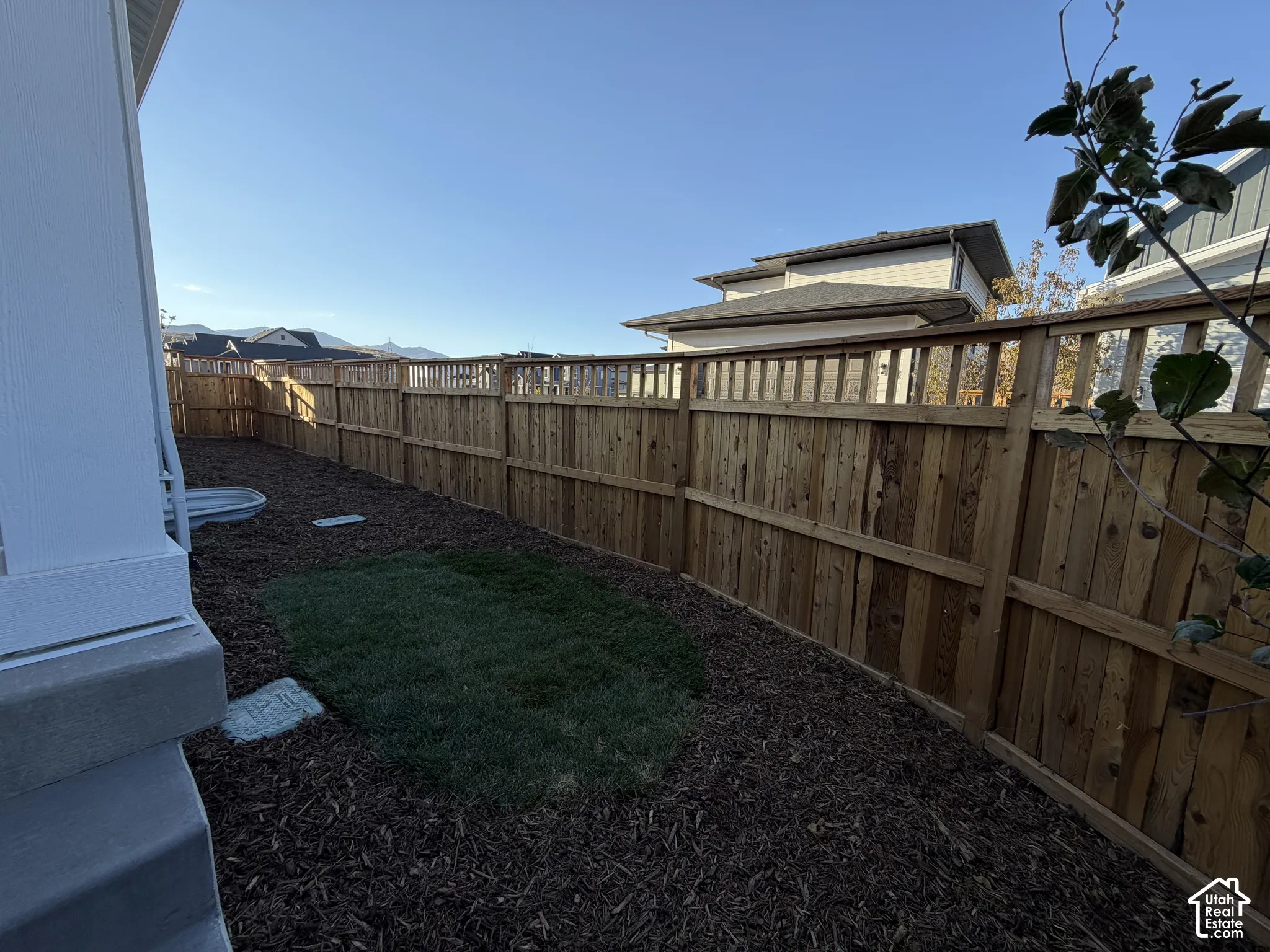 Private yard space with wood fencing, a dedicated grass area, and landscaped with wood chips