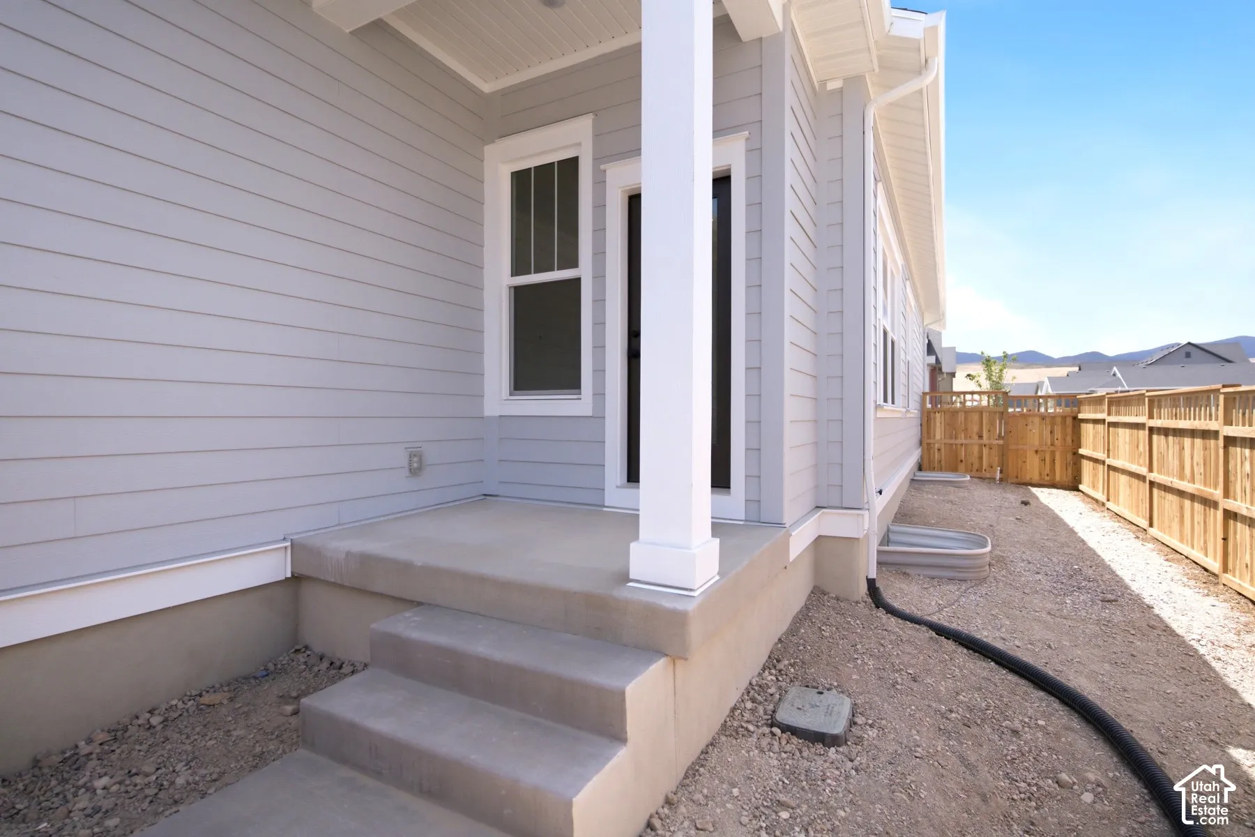 Concrete porch with steps, vinyl siding, white trim, and a fenced yard