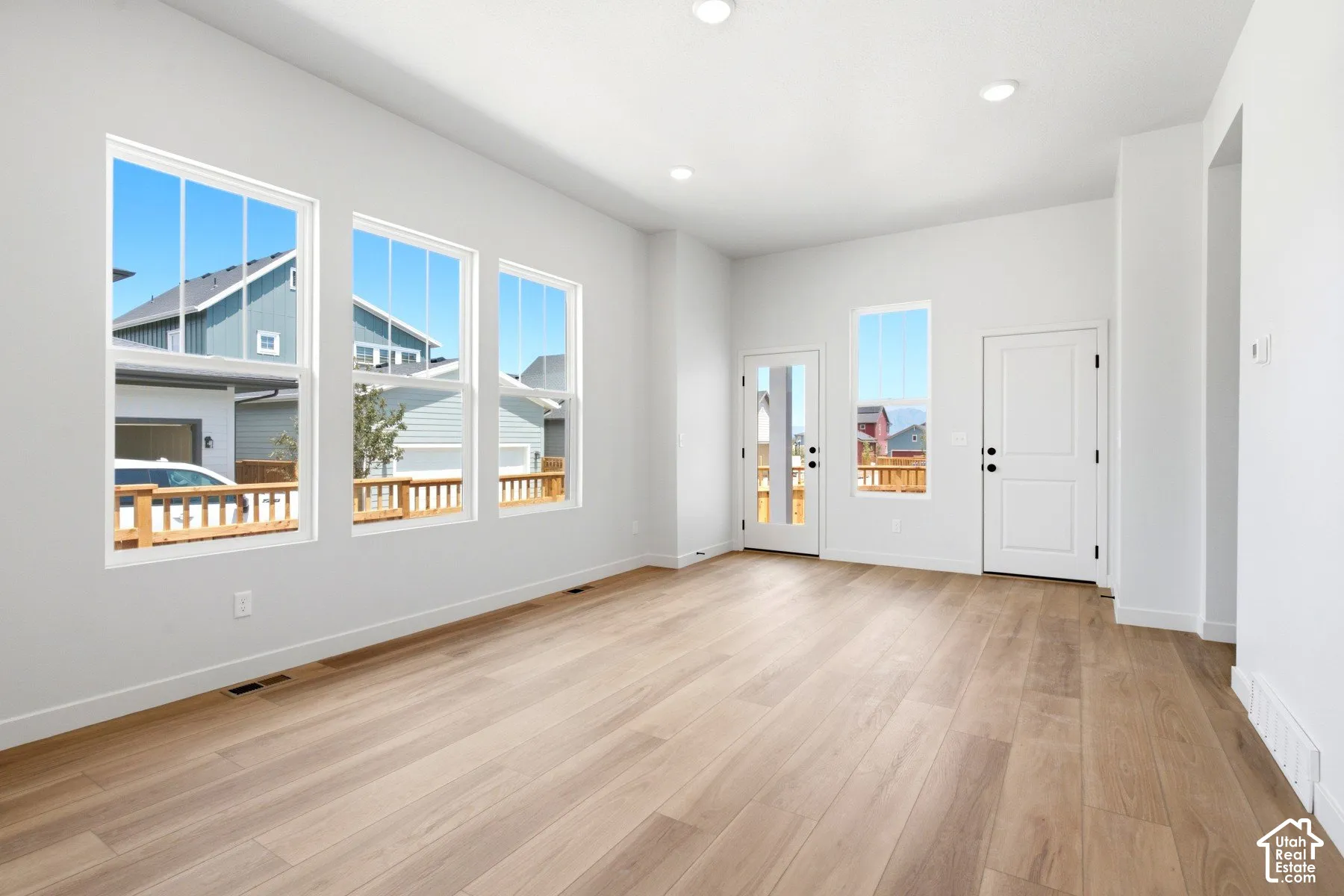 Open concept living area with light wood-finish flooring, recessed lighting, and multiple large windows