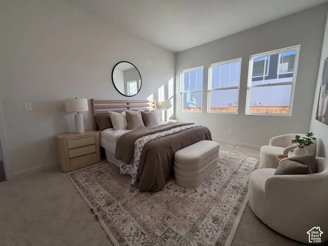 Vaulted ceiling, light neutral wall color, three large windows, recessed lighting, and carpet flooring
